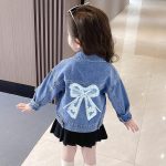⁦آشر فاشن جاكيت جينز للبنات بتصميم فيونكة ثلاثي الابعاد مزين بالزهور⁩ - الصورة ⁦2⁩