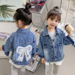⁦آشر فاشن جاكيت جينز للبنات بتصميم فيونكة ثلاثي الابعاد مزين بالزهور⁩ - الصورة ⁦3⁩